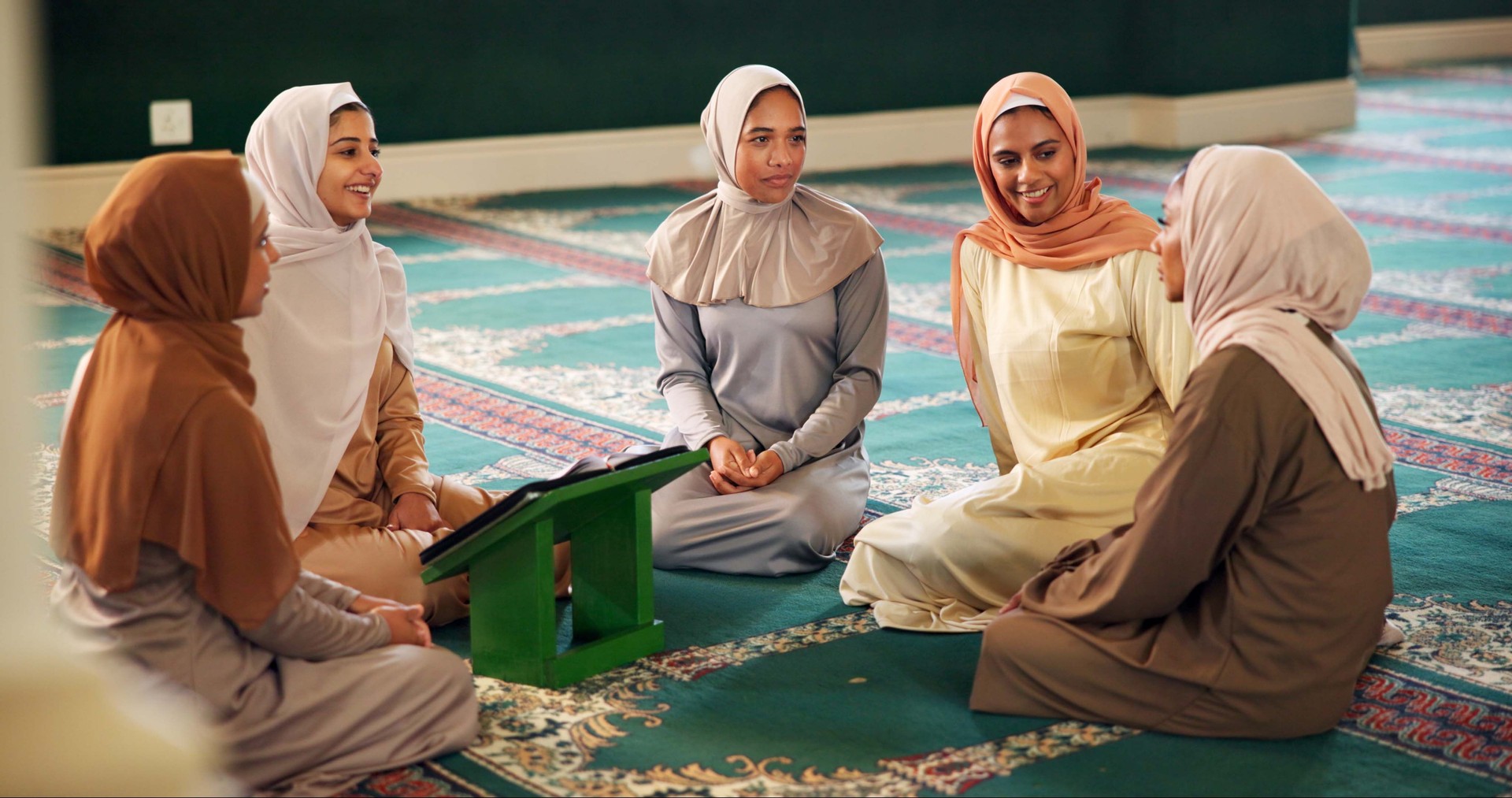 Friends, talking or Muslim women in mosque learning to worship for gratitude or support. Chat, Islamic faith and spiritual people with quran book for God on Ramadan for studying together